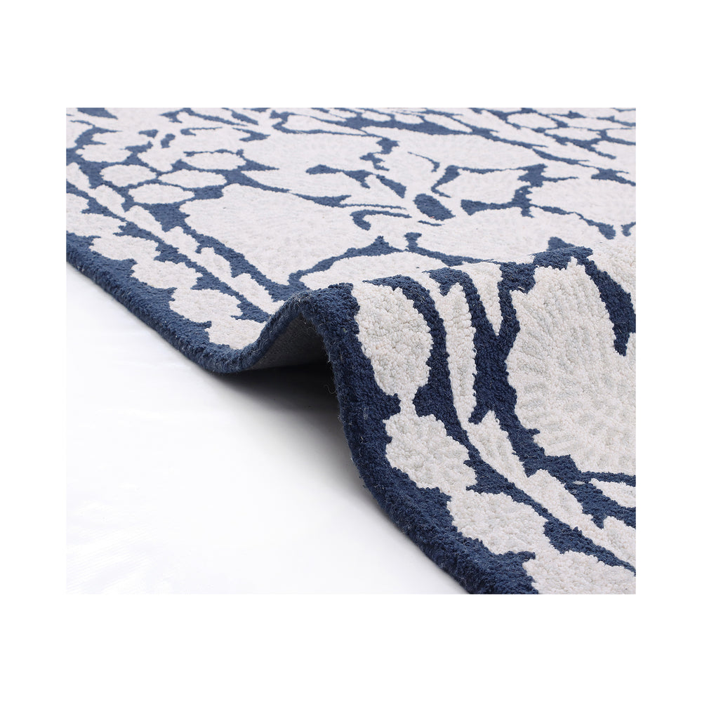 Corner of the Chinoiserie rug folded back to show the dense ivory wool pile and navy underside