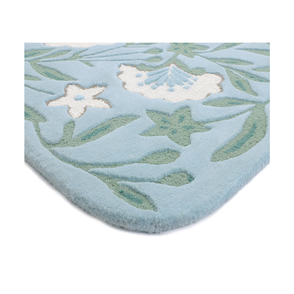 Folded edge of the Garden wool rug showing the binding and botanical pattern
