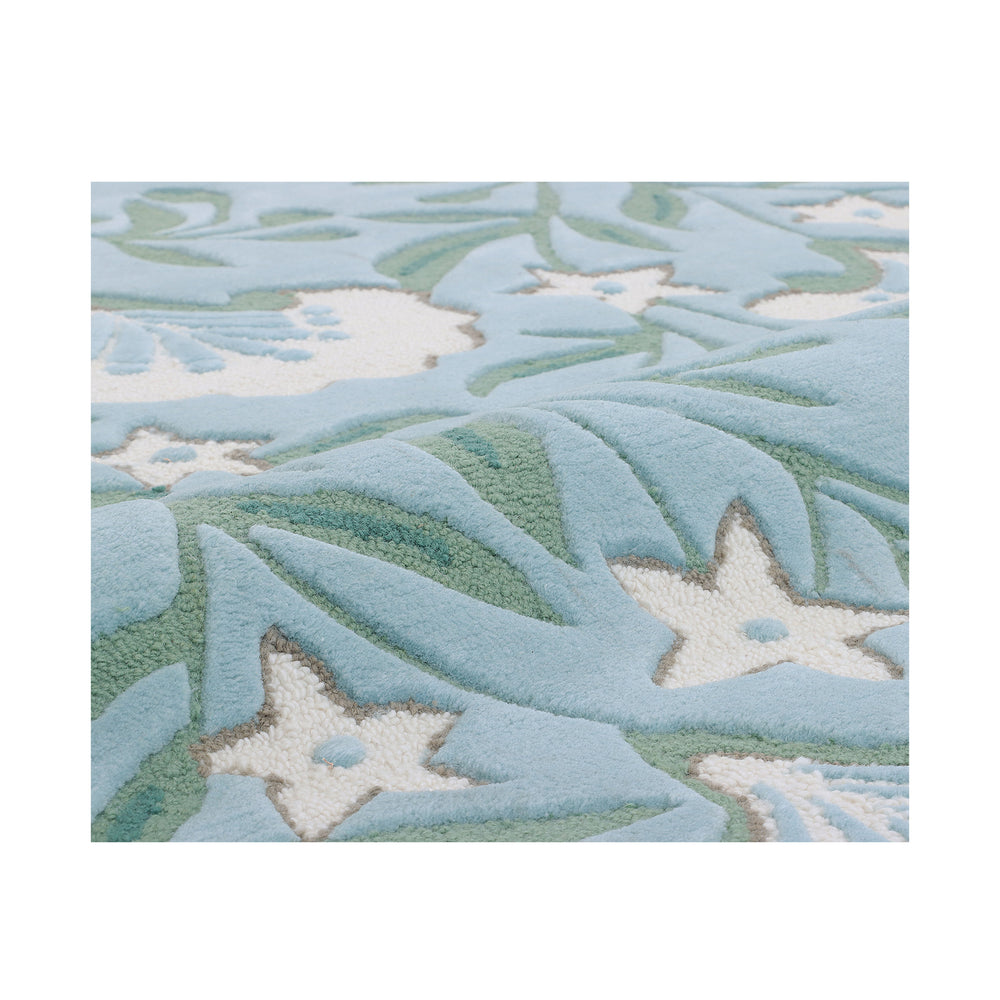 Close-up of the cream blossom and sage vine motif on the blue ground of the Garden rug